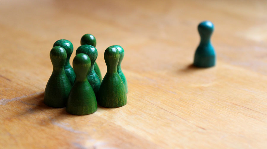 Play figures, several green ones in a group and one blue on the side.