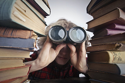 Man with binoculars between two stacks of books