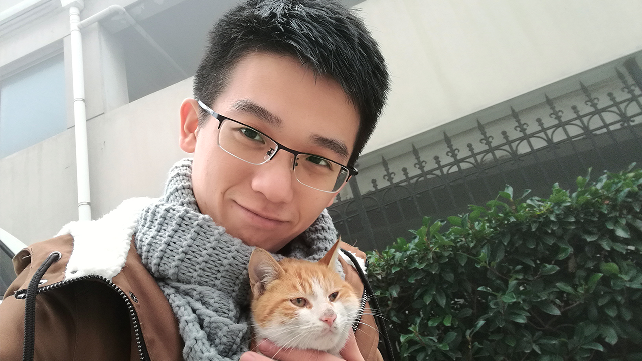 Boqian Wang med en orange katt i famnen.