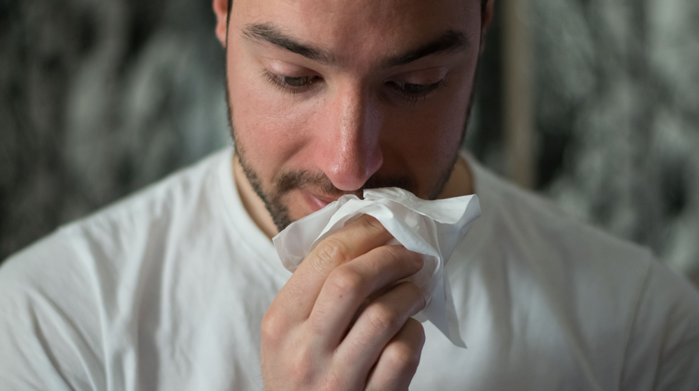 Man blowing his nose.