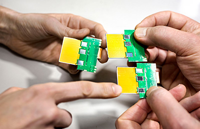  Four hands hold three silicon sensors.