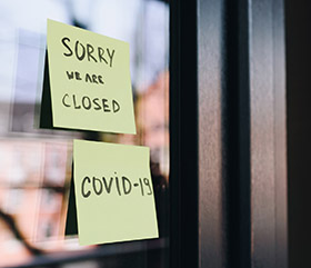 Bild med två post it-lappar på en dörrs glasruta. På dessa står det Sorry we are closed samt covid-1