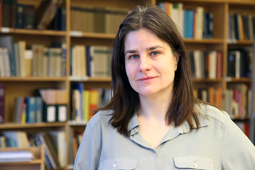 Portrait photo: Anita Kullen in front of a bookshelf.