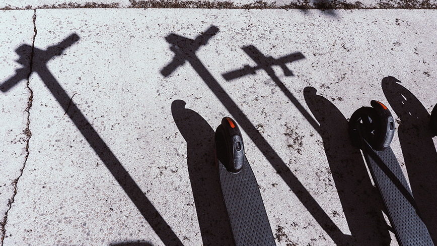 Electric scooters and pavement with sharp shadows.