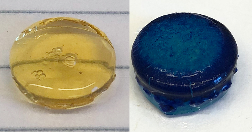 Two pellets, one translucent and golden, the other opaque and dark blue.