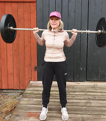 A young woman with a barbell on her shoulders.