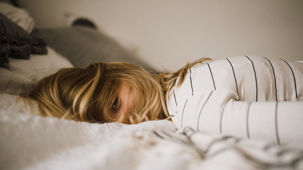 Woman lying in bed, very tired. 