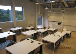 Lecture hall with oblong tables gradually raised. 4 chairs per table.