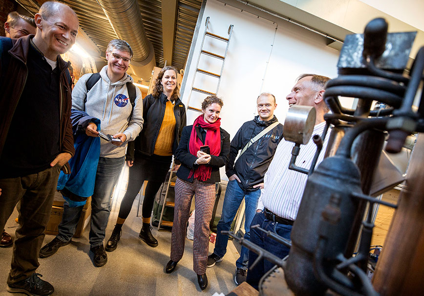 En grupp människor som tittar på en prototyp av ett 100 år gammalt kylskåp.