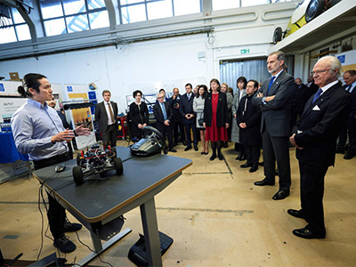 A group of people in front of a man showing a car model.