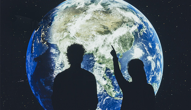 Young peoplein front of a screen showing the globe.