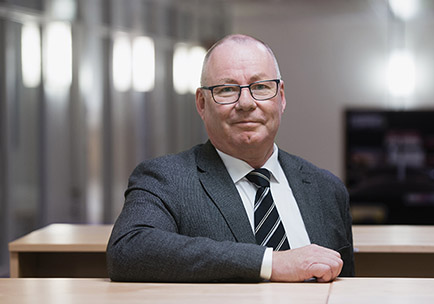 A man wearing a grey suite and a tie.