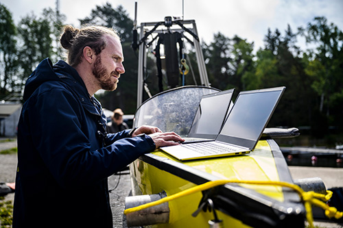 En person står framför två laptops som är placerade på en testbåt.