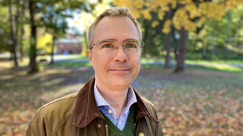 Andrew Martin in front of some trees with yellow leaves.