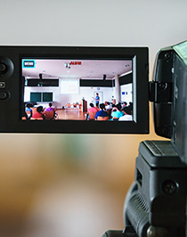 En föreläsning syns genom en videokamera.
