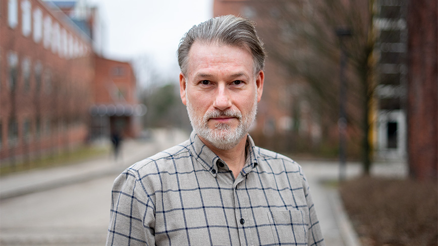 Man outdoors with checkered shirt. 