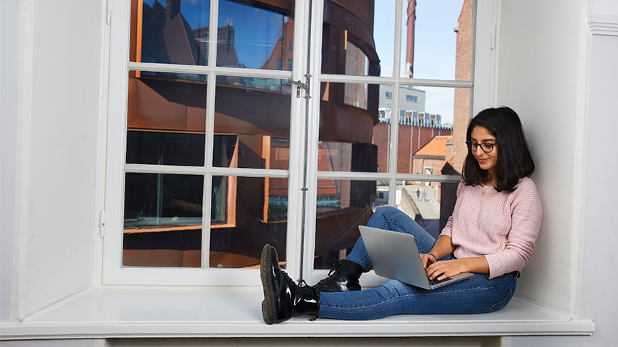 Female student sitting in a window. 