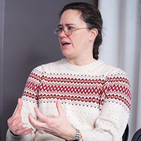 Woman sitting at a table gesturing.