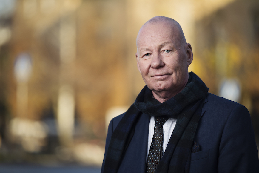 Photo: Man in darkblue jacket and scarf. Blurred background.