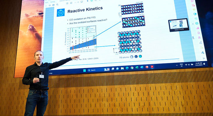 A man presenting in front of a big screen.