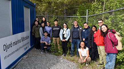 a group of people standing by a sign with the text Djurö Marine Field Station