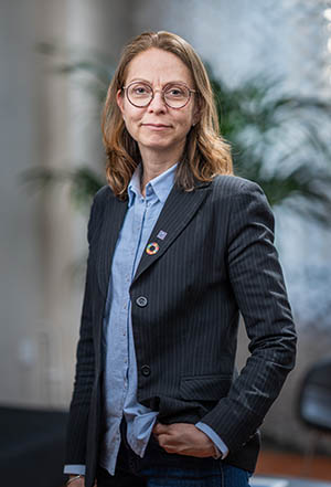 Portrait photo: A woman in long brown hair and glasses.