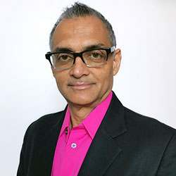 A man with dark hair, glasses, a black jacket ,and a cerise blouse.