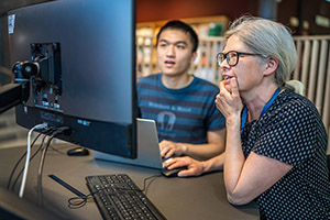Librarian and doctoral student sitting in front of a screen discussing