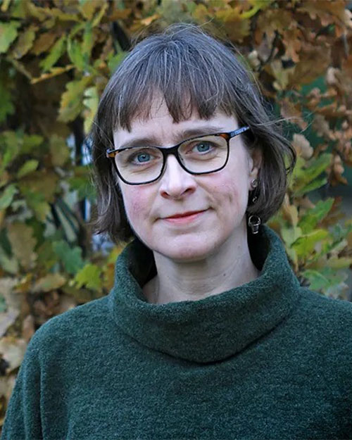 Woman with glasses and a fringe and green jumper.