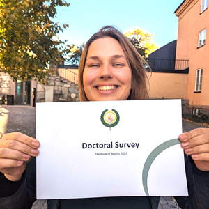 Young woman holding a sign with Doctoral survey 2023.