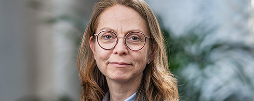 Porträttbild: En kvinna i axellångt hår och glasögon.