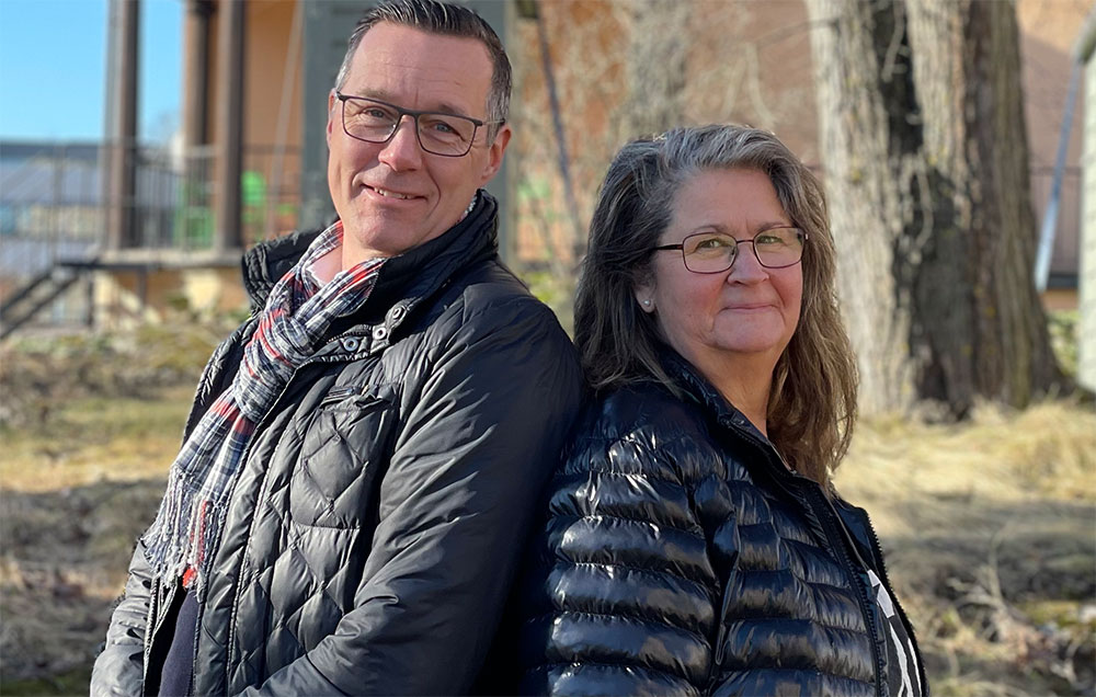 Porträttbild: En man och en kvinna klädda i mörkablå täckjackor med ryggarna snett mot varandra.