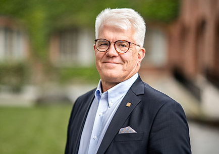 Portrait Photo: Stefan Östlund, a man with white hair and glasses.