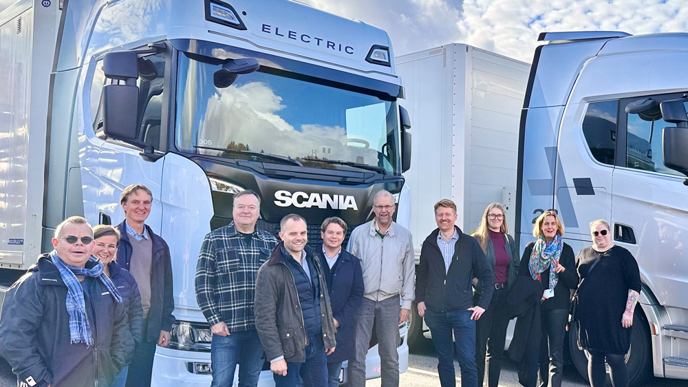 Gruppfoto framför Scania-lastbilar.