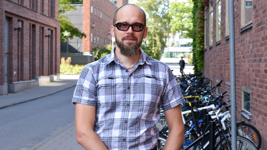 Patrik Hilber står framför cykelställ på campus.