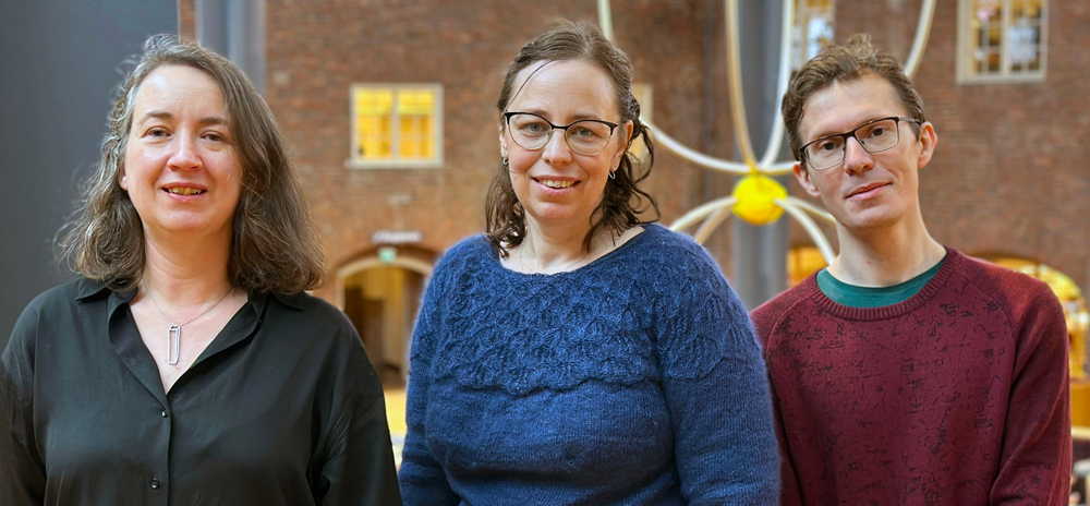 Tre personer i biblioteksmiljö