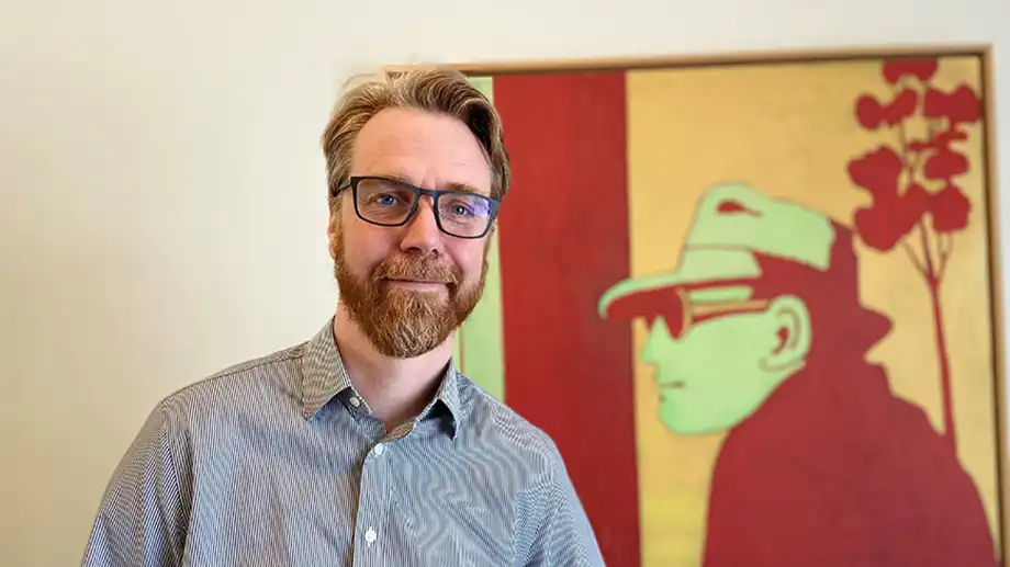 Man stående framför vägg och tavla.