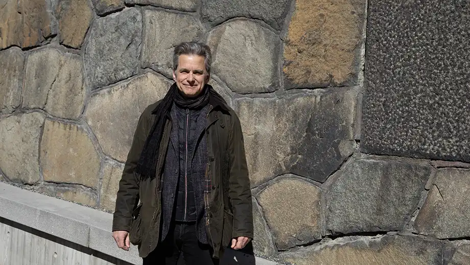 Man in front of stone wall.