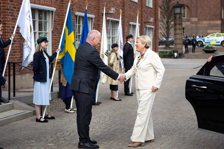 En man hälsar på en kvinna på en borggård.