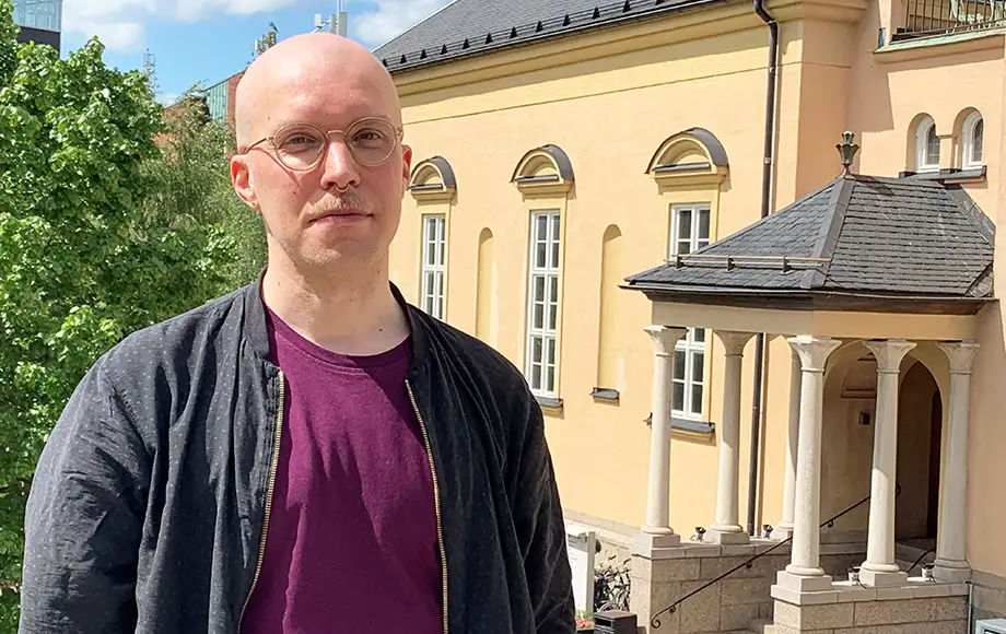 Roh Petas in front of a yellow house facade.