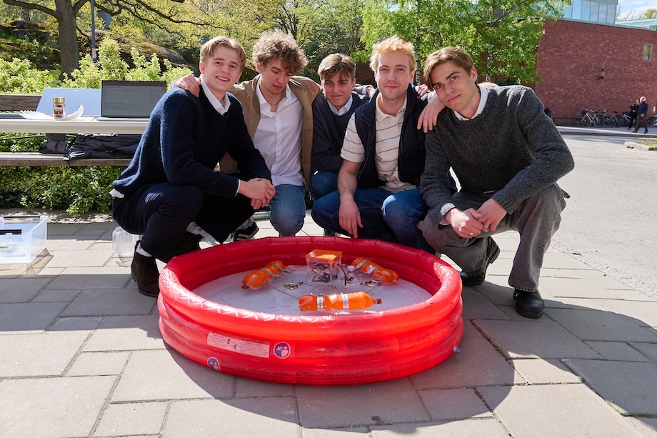 Foto: 5 killar bakom sin robot som flyter i en gummipool.