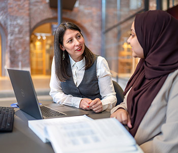 En bibliotekarie och student ler mot varandra. 