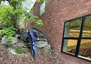 Man pointing at stone pile next to a building.