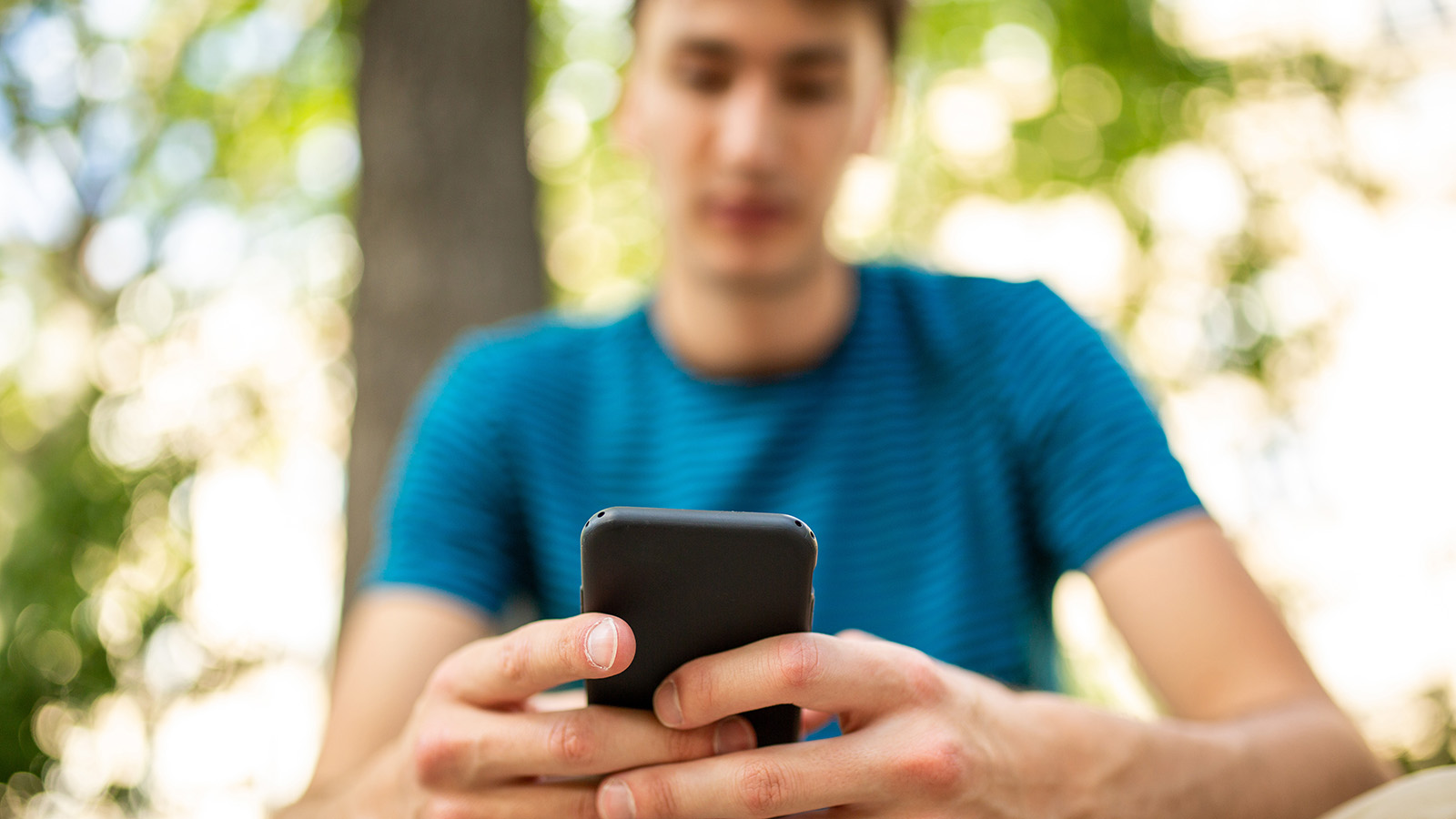 Young person using smart phone in outdoor setting 