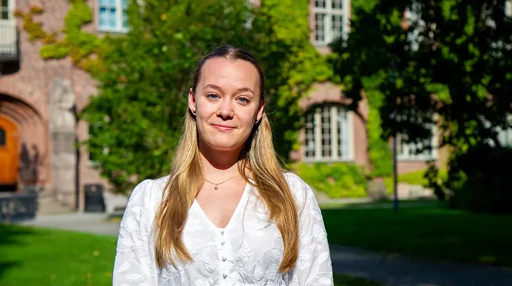 Kvinna mot grön gård med byggnader.