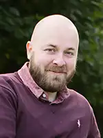 Man med skägg i lila tröja.