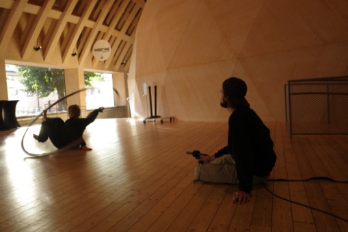 Alva and Elias performing on a wooden floor outside the dome structure with bright natural