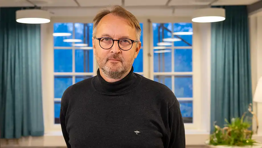 Man framför fönster med gardiner.