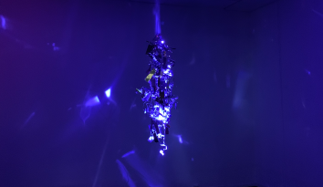 Blue image with a hanging structure reflecting light on surrounding walls