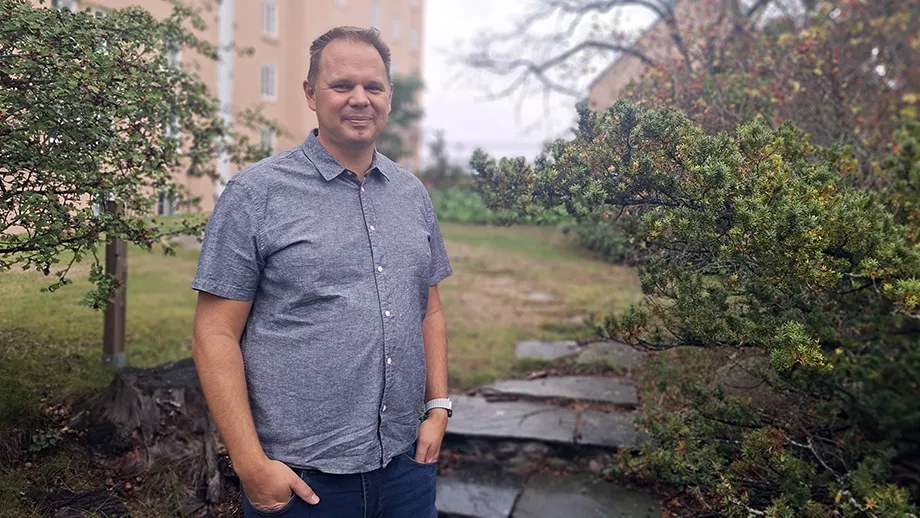A man in front of some steps and bushes.